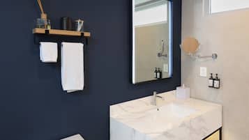 A modern bathroom with a marble sink, a large mirror, and a towel rack with two towels.