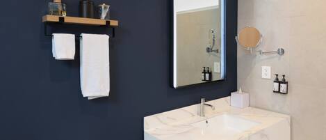 Un baño moderno con un lavabo de mármol, un espejo grande y un perchero con dos toallas.
