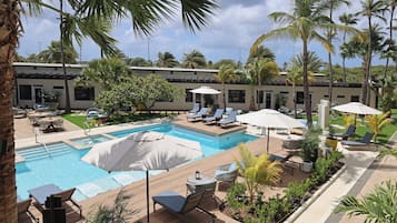 Ein Poolbereich mit Liegestühlen, Sonnenschirmen und Palmen.