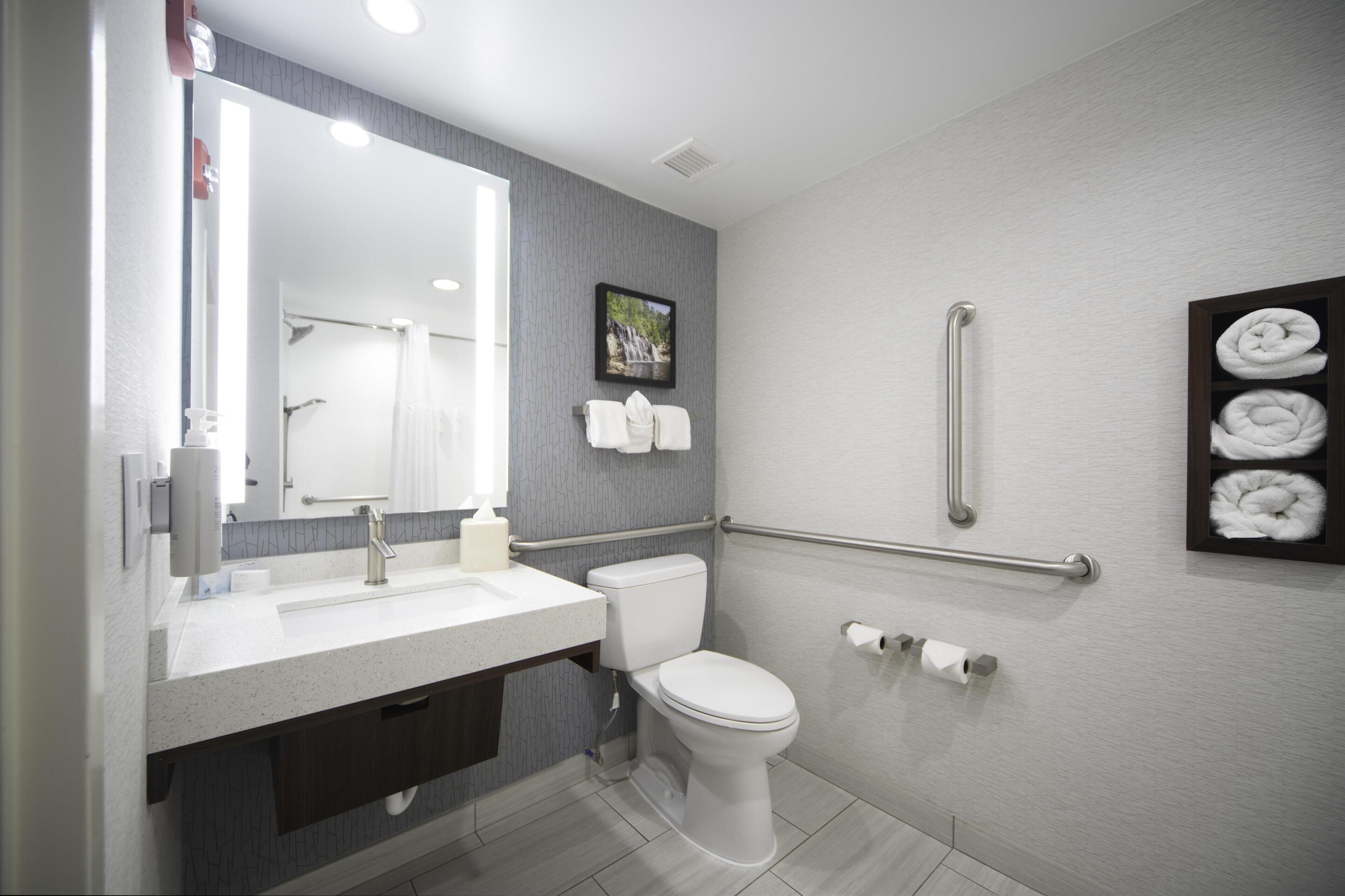 Un baño moderno con un lavamanos, inodoro y toallero blancos.