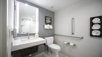 Un baño moderno con un lavamanos, inodoro y toallero blancos.