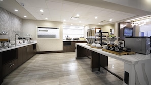 A modern kitchen with a marble countertop, stainless steel appliances, and a large window providing natural light.