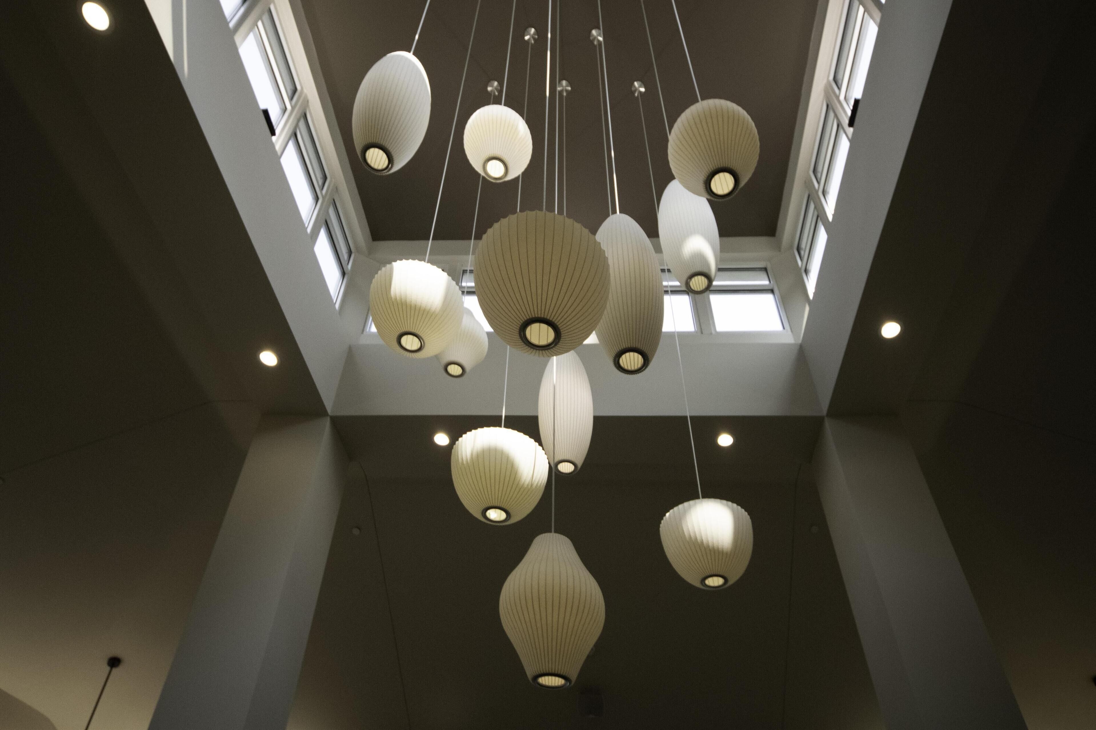 Un intérieur moderne agrémenté de plusieurs luminaires suspendus et de grandes fenêtres qui laissent entrer la lumière naturelle.