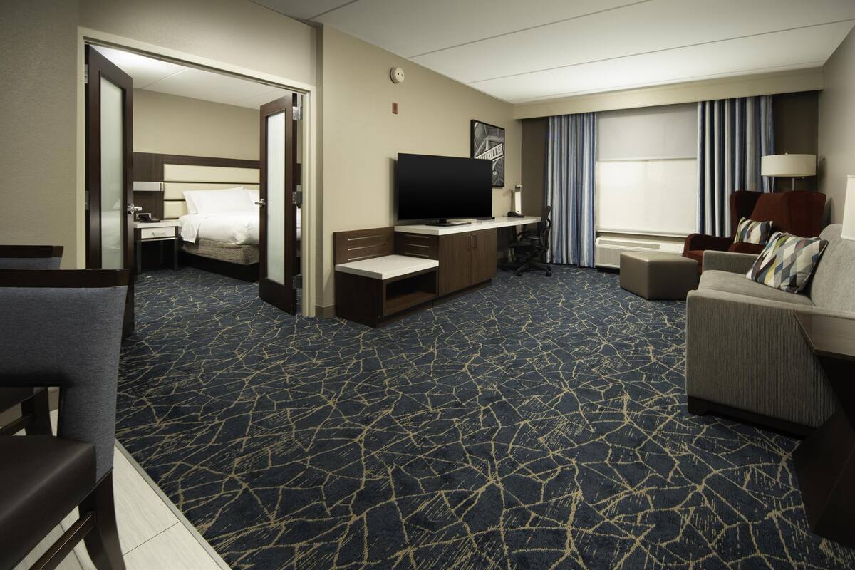 Habitación de hotel con cama, escritorio, televisor, sofá y sillón.
