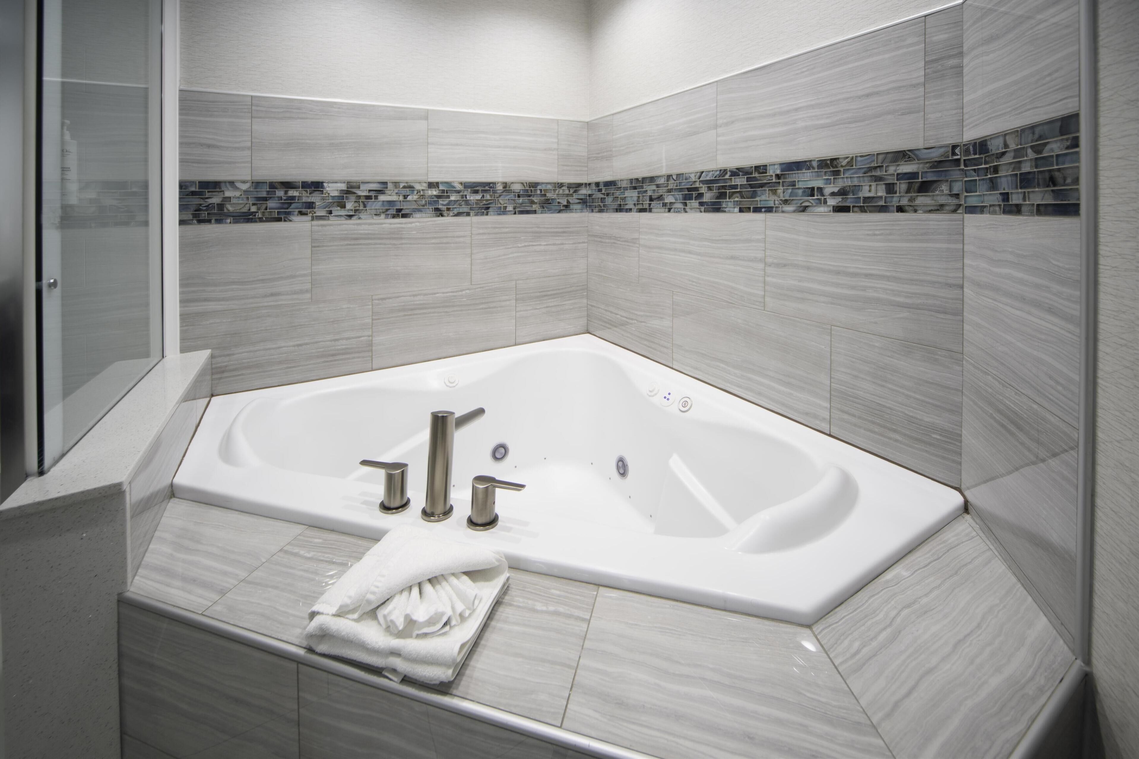 A modern bathroom with a large bathtub, a glass shower enclosure, and a tiled backsplash.