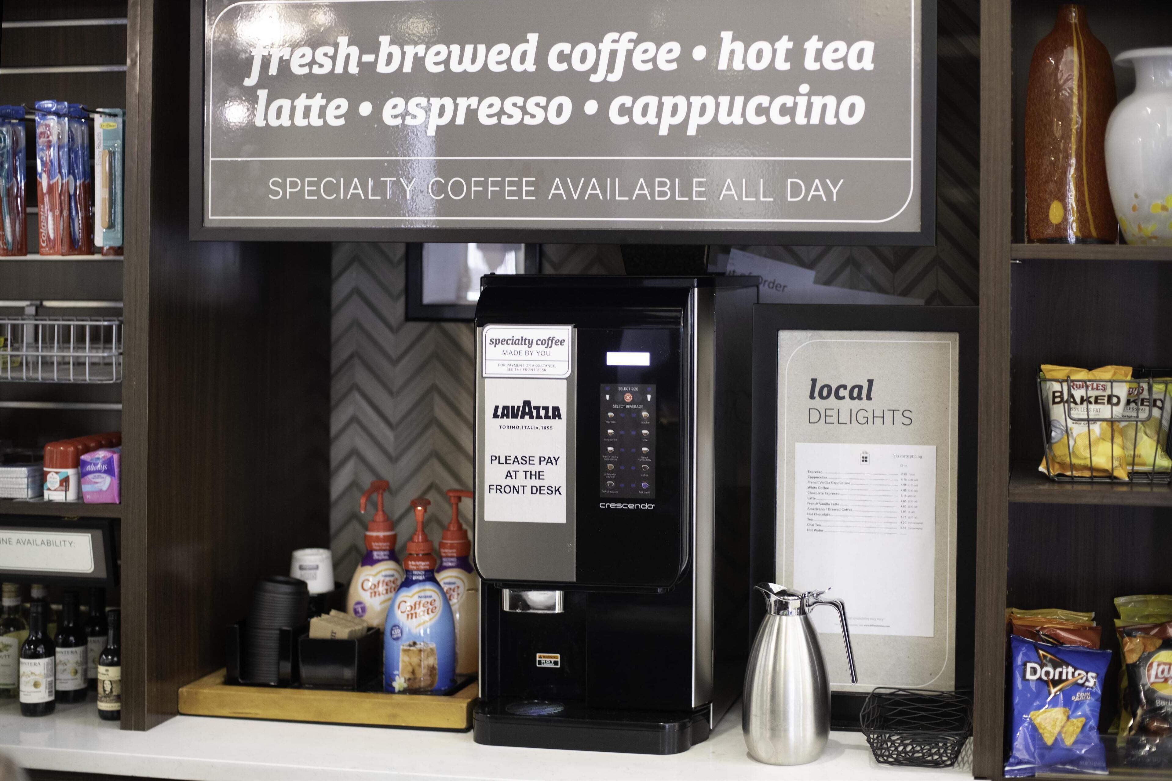 Un espace dédié aux cafés de spécialité, avec une machine à café, un panneau publicitaire annonçant du café fraîchement préparé et un menu présentant les spécialités locales.