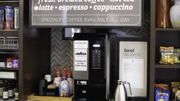Un espace dédié aux cafés de spécialité, avec une machine à café, un panneau publicitaire annonçant du café fraîchement préparé et un menu présentant les spécialités locales.