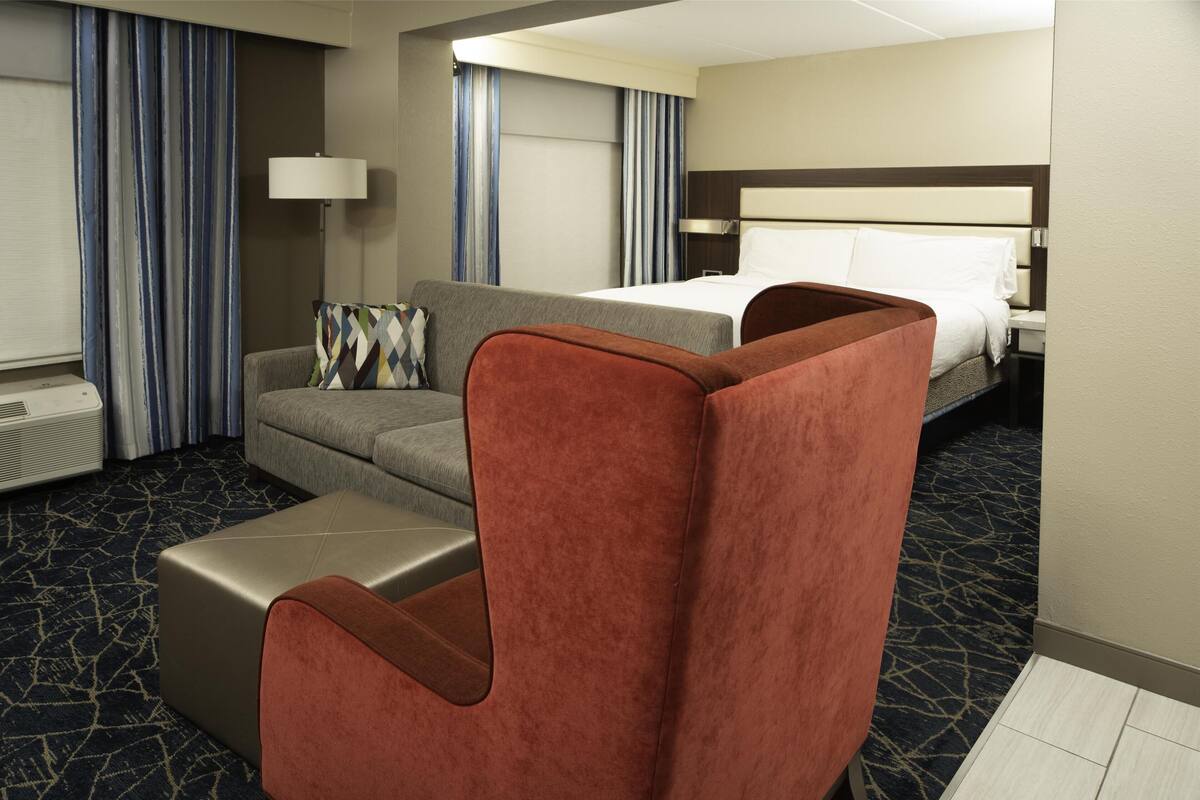 Una habitación de hotel con una cama, un sofá, una silla y una lámpara.