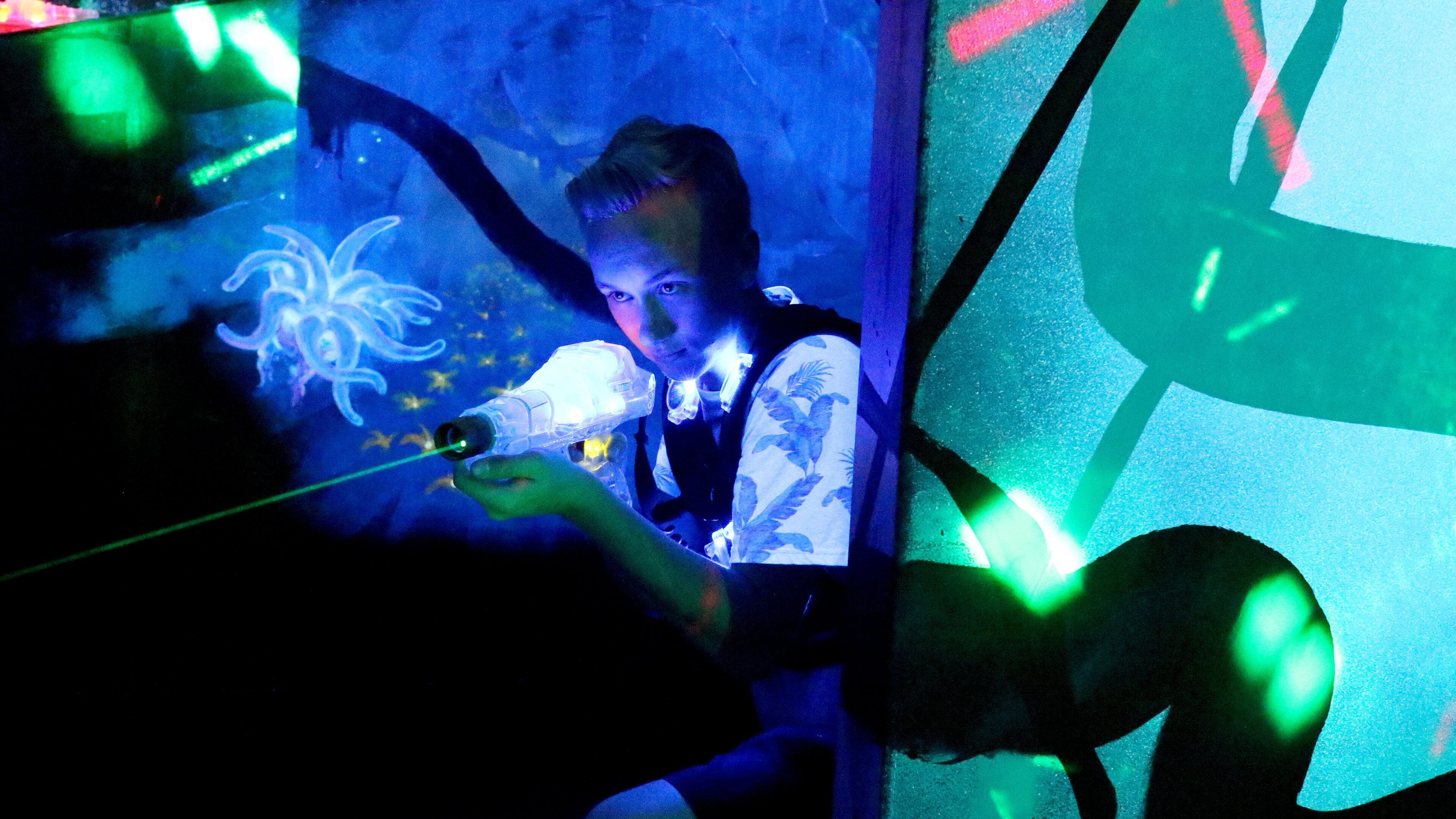 A person holding a laser pointer in a dimly lit room with a projection screen.