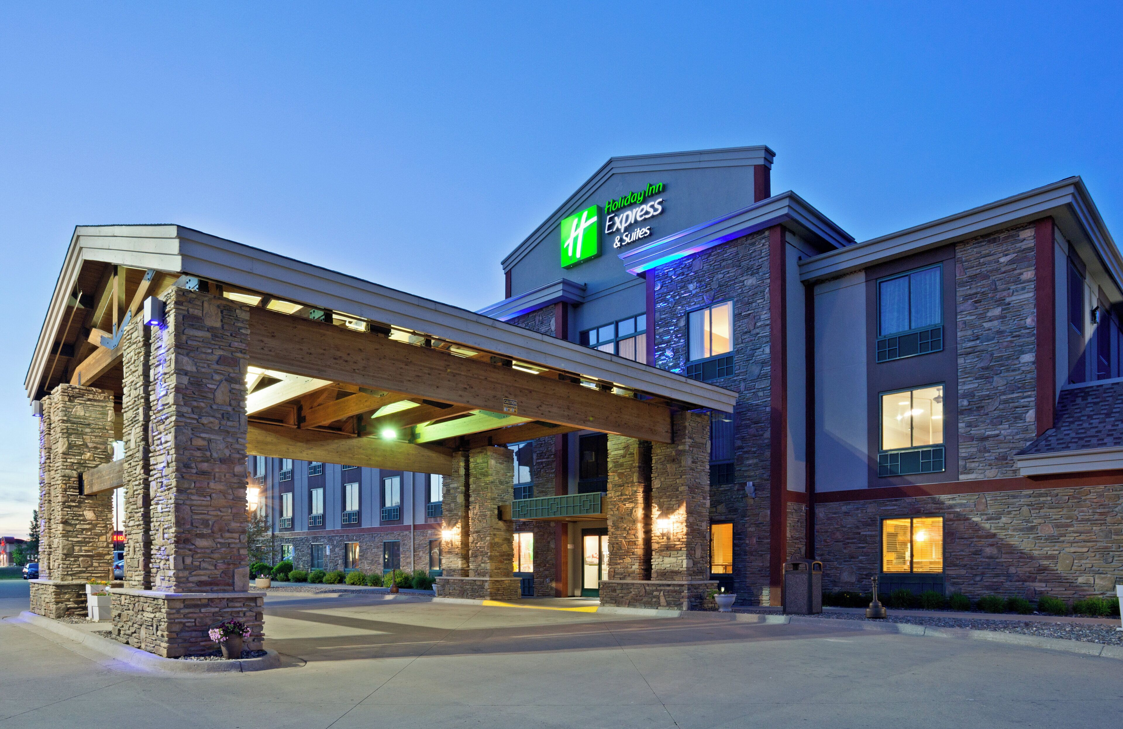 A Holiday Inn Express & Suites with a covered entrance, stone facade, and multiple windows.