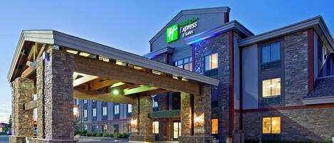 A Holiday Inn Express & Suites with a covered entrance, stone facade, and multiple windows.