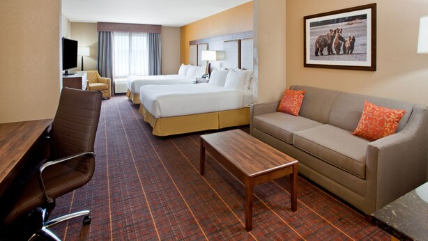 A hotel room with two beds, a sofa, a desk, a chair, and a television. - Holiday Inn Express Hotel & Suites Brainerd-Baxter by IHG (Brainerd)