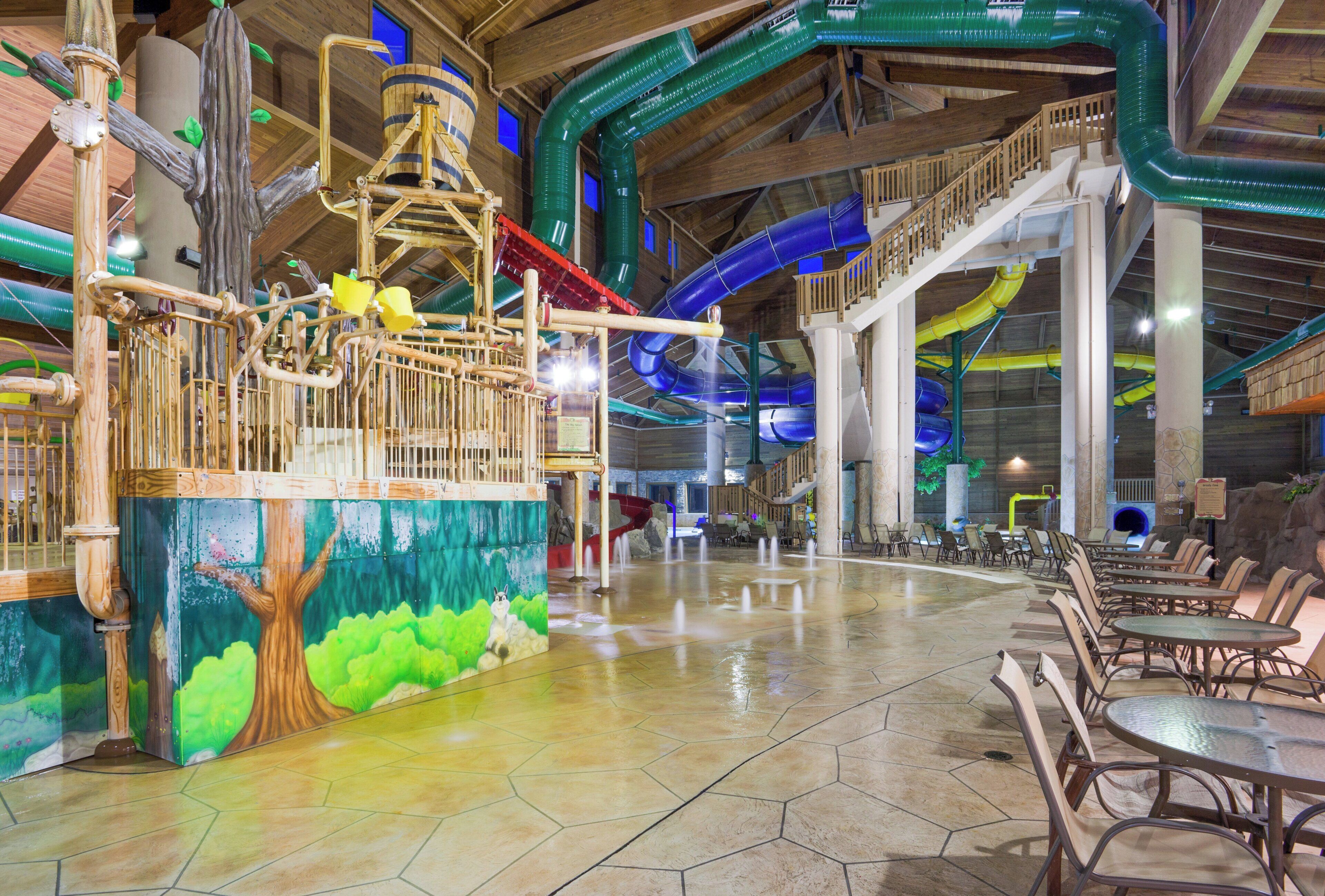 A spacious indoor area with a water feature, seating arrangements, and a mural of a tree.
