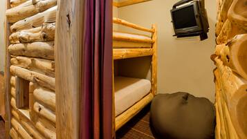 Ein Blockhauszimmer mit Etagenbett, einem an der Wand befestigten Fernseher und einem runden Sitzsack.