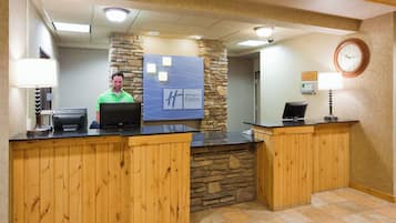 Un mostrador de recepción con una computadora, un reloj y un letrero que indica Holiday Inn Express.