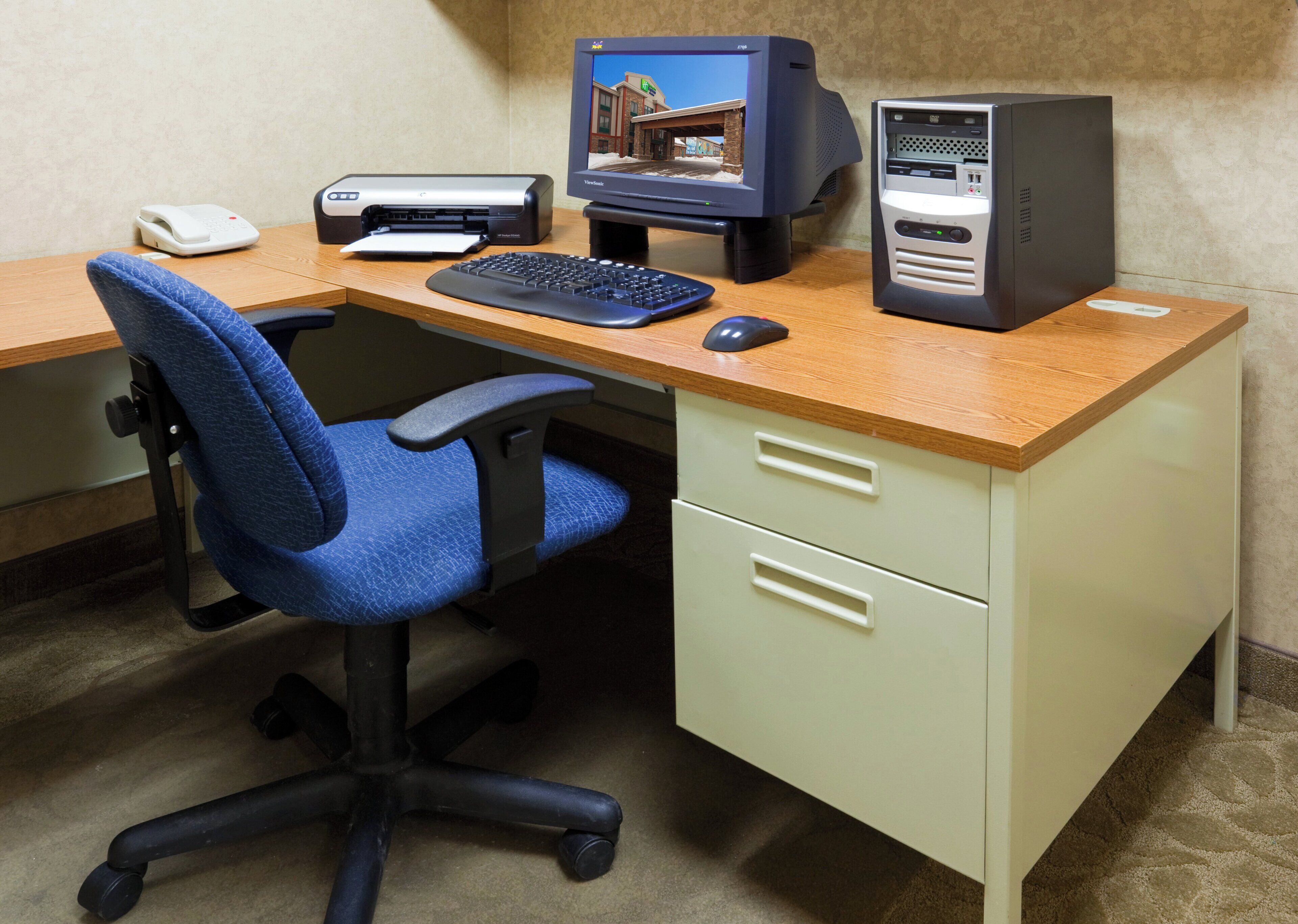 A desk with a computer, keyboard, mouse, and a scale.