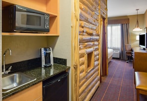 A compact hotel room with a kitchenette, including a microwave, coffee maker, and sink.