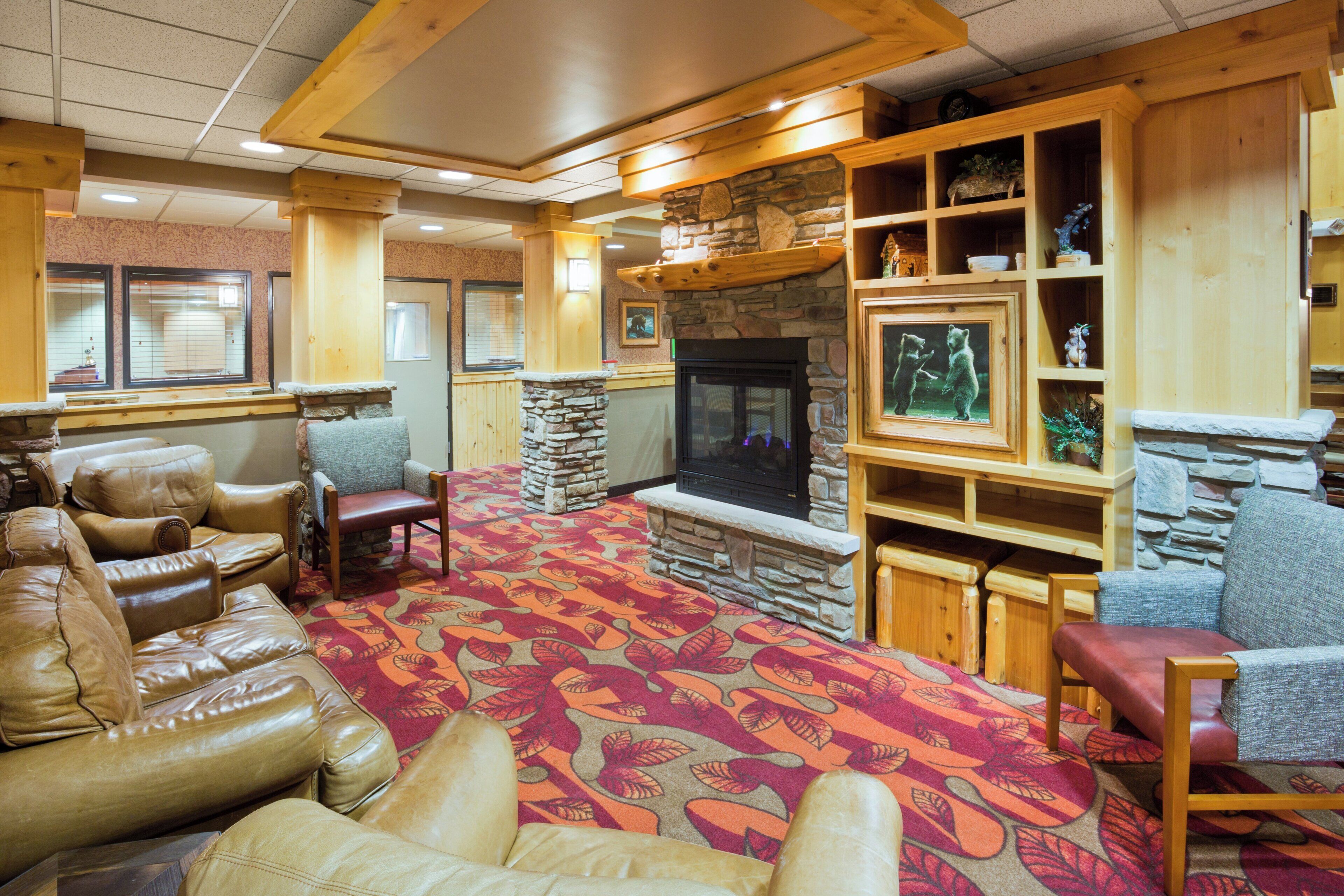 A cozy living room with leather sofas, a fireplace, and a stone accent wall.