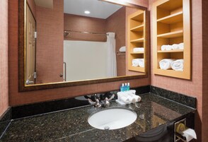 Un baño con lavamanos, espejo y repisas para toallas.
