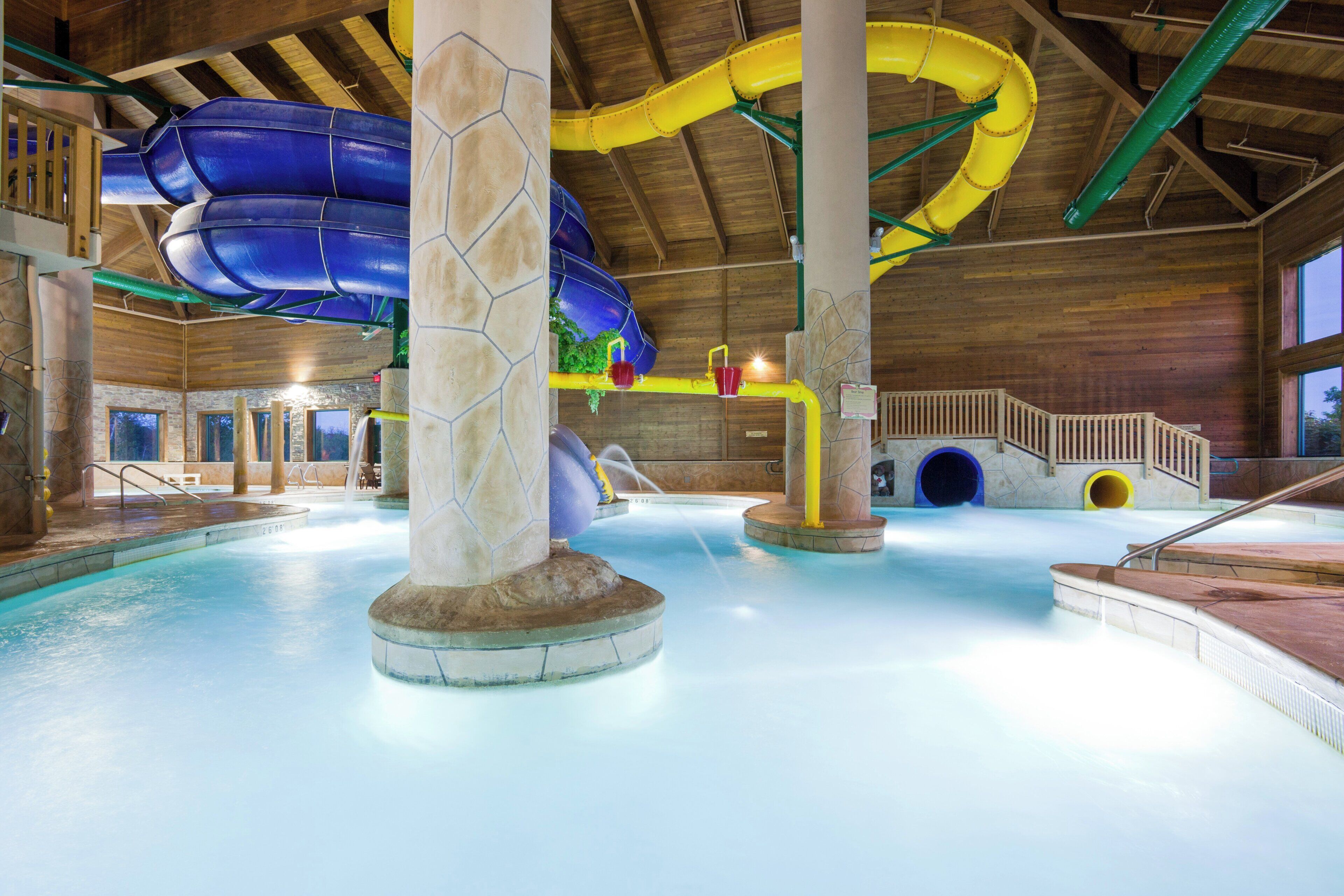 Parque acuático interior con múltiples toboganes y zona de piscina.