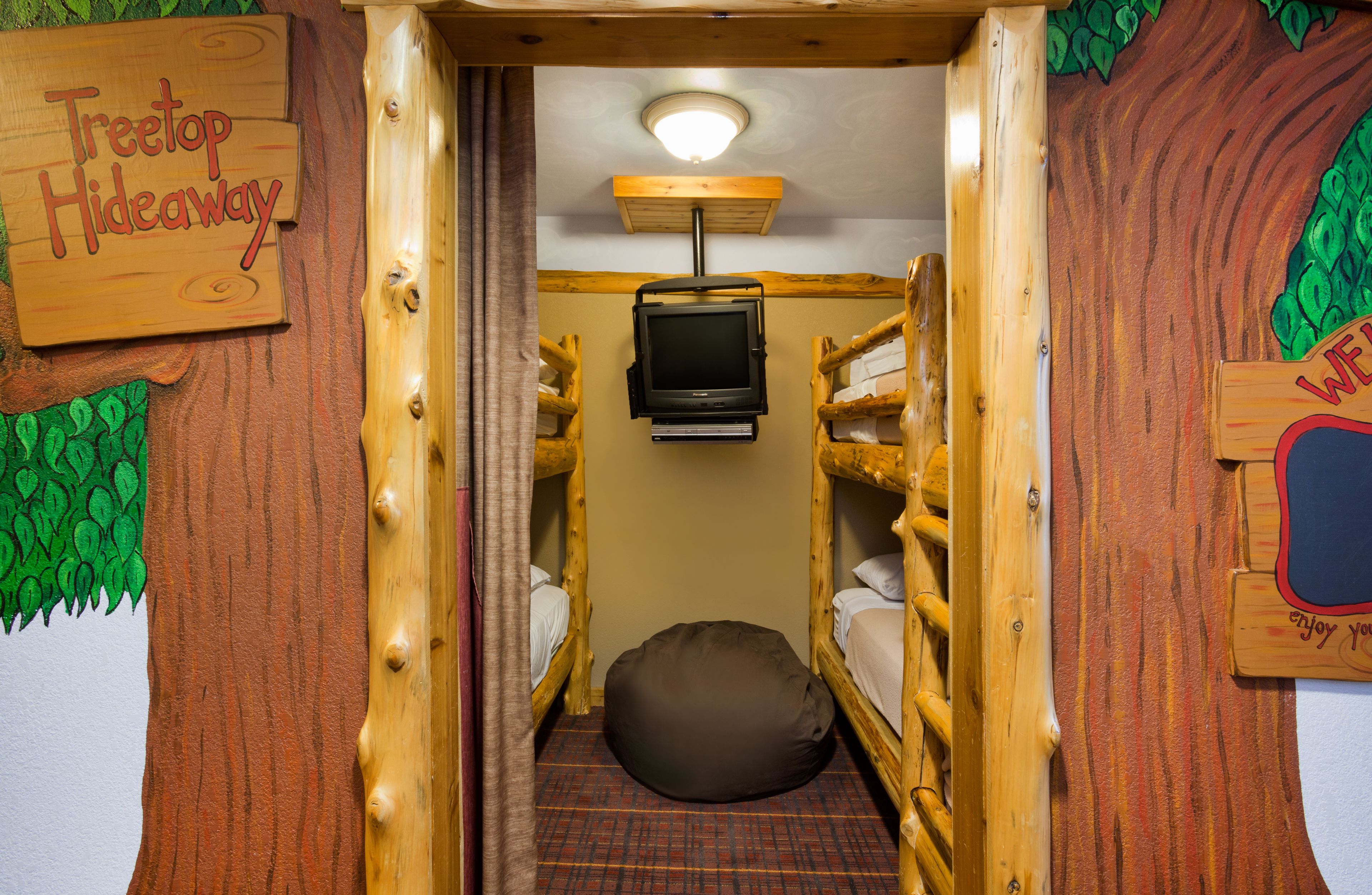 A cozy room with bunk beds, a television, and a sign reading "Treetop Hideaway."