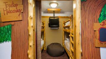 A cozy room with bunk beds, a television, and a sign reading "Treetop Hideaway."