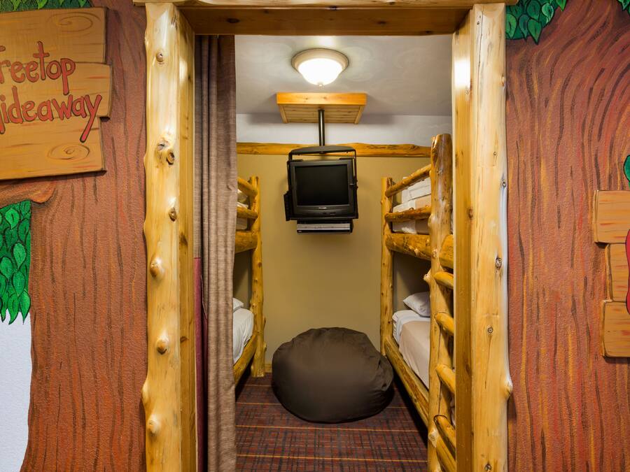A cozy room with bunk beds, a television, and a sign reading "Treetop Hideaway."