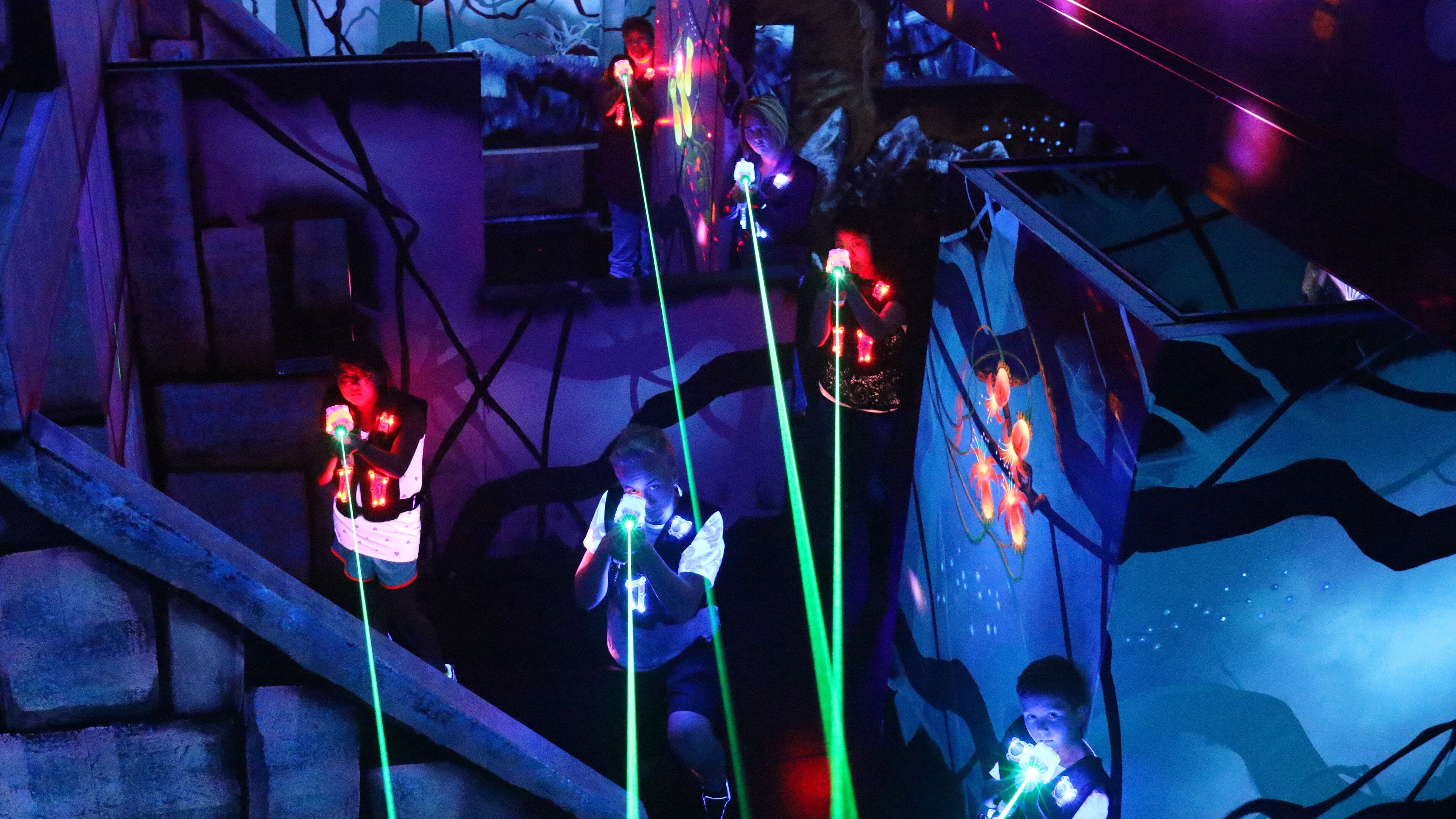 Un grup de persones en una sala poc il·luminada amb un escenari i un fons.