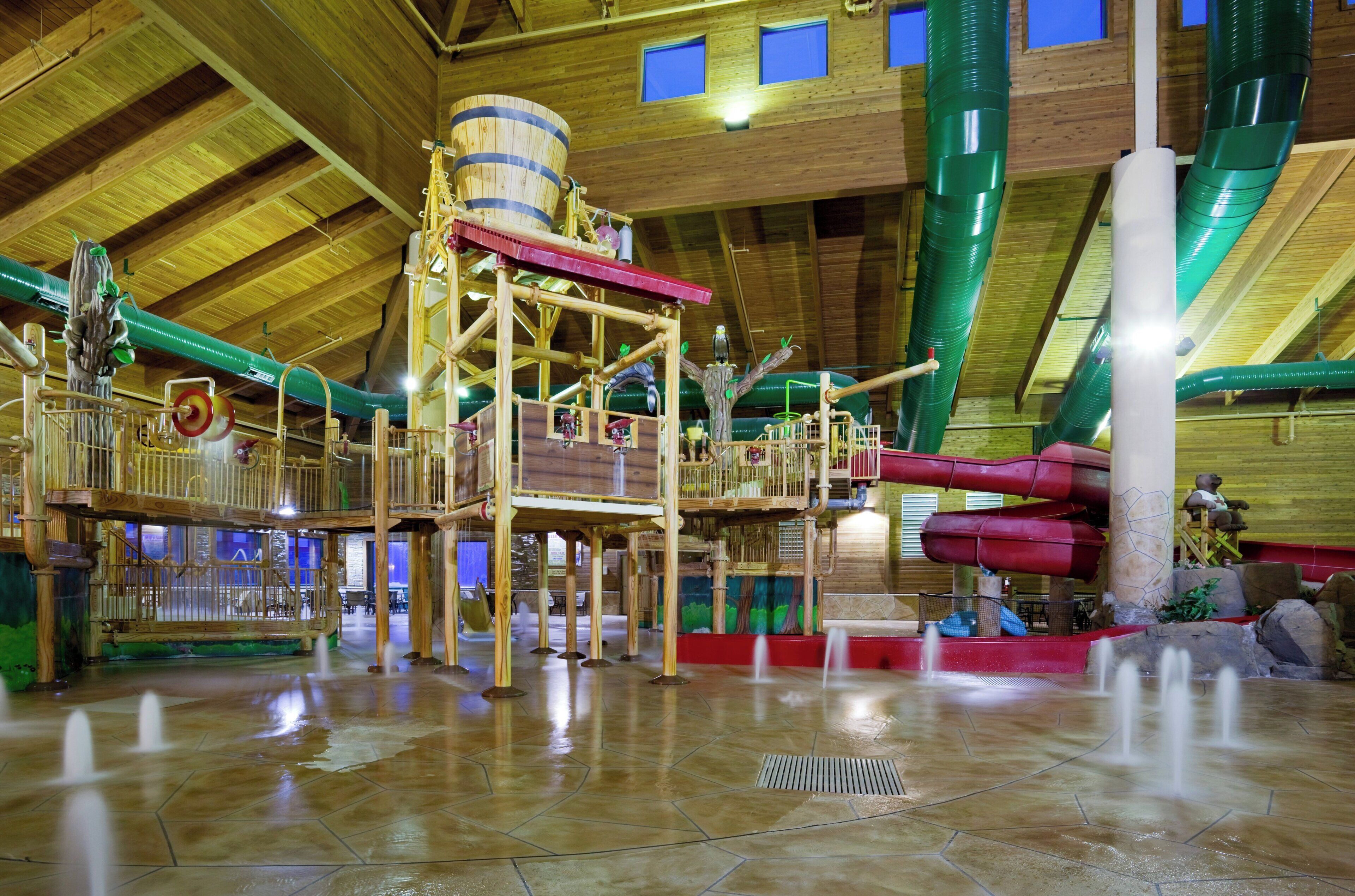 An indoor water park with wooden structures, slides, and a high ceiling.