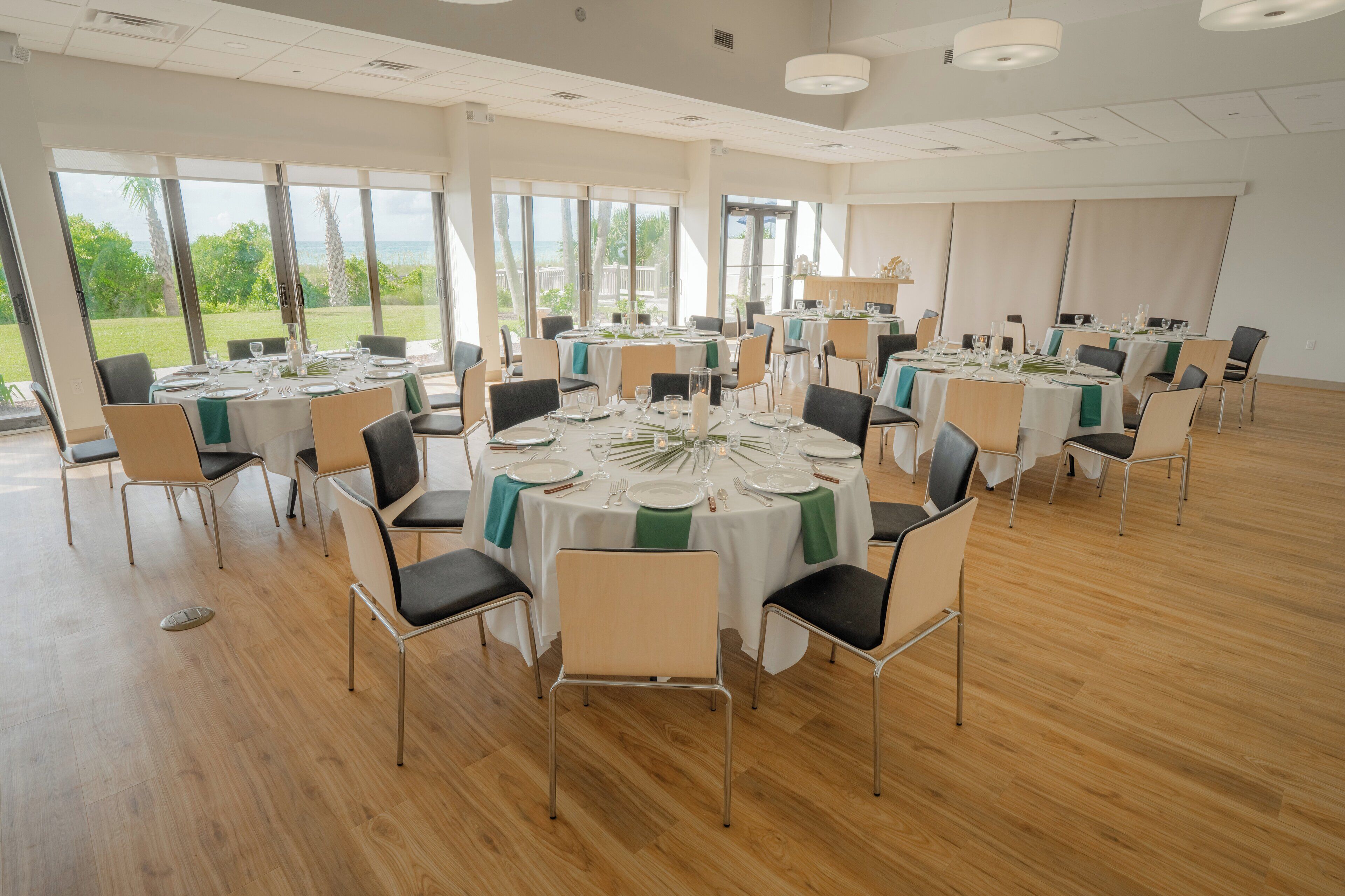 Un vaste espace dédié à la salle à manger, avec des tables rondes, des chaises et de grandes fenêtres donnant sur l’extérieur.