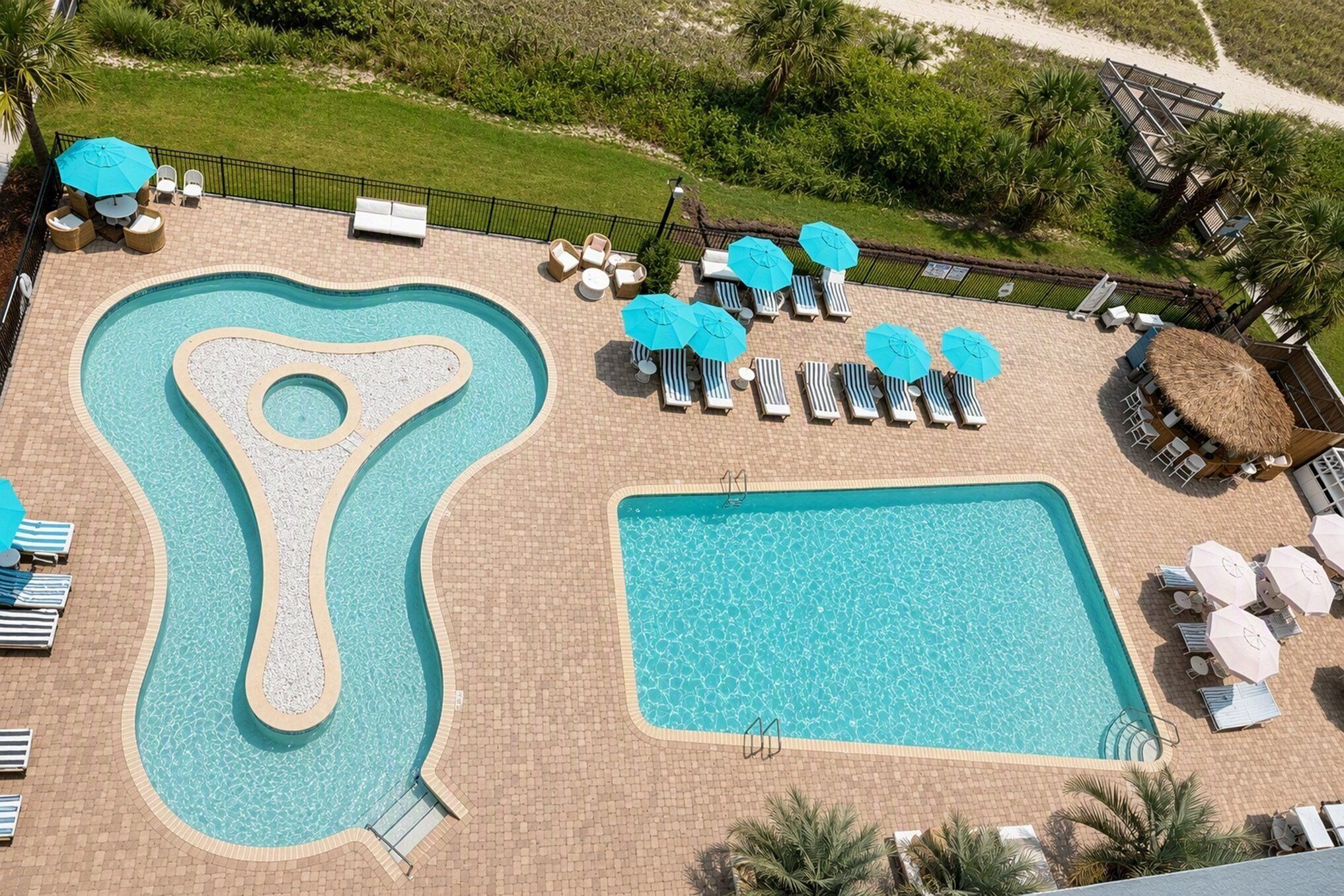 A swimming pool with a unique shape, surrounded by lounge chairs and umbrellas.
