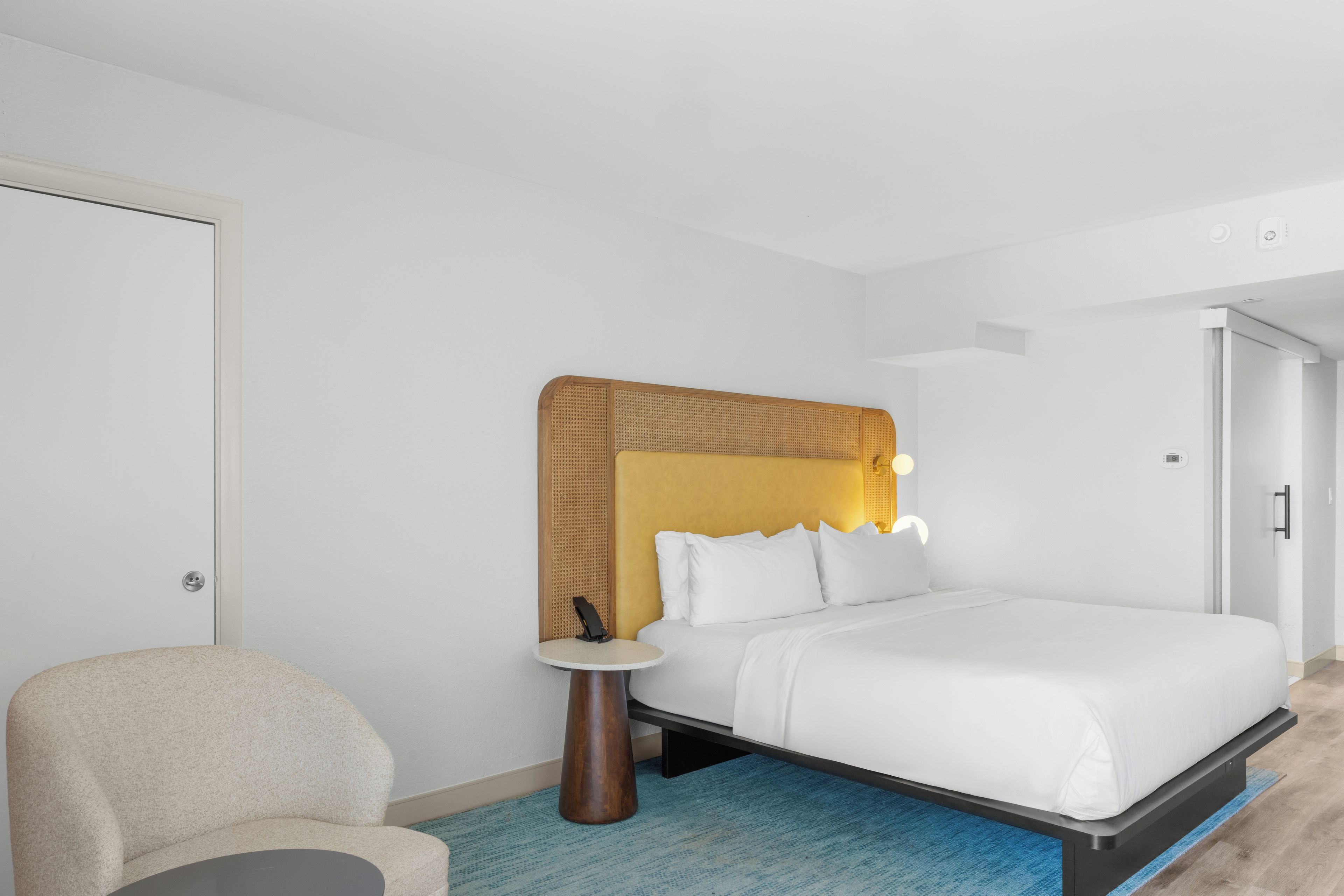 A hotel room with a bed, a chair, and a small table.