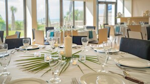 A dining table set for a meal with candles, glasses, and plates, overlooking a scenic view.