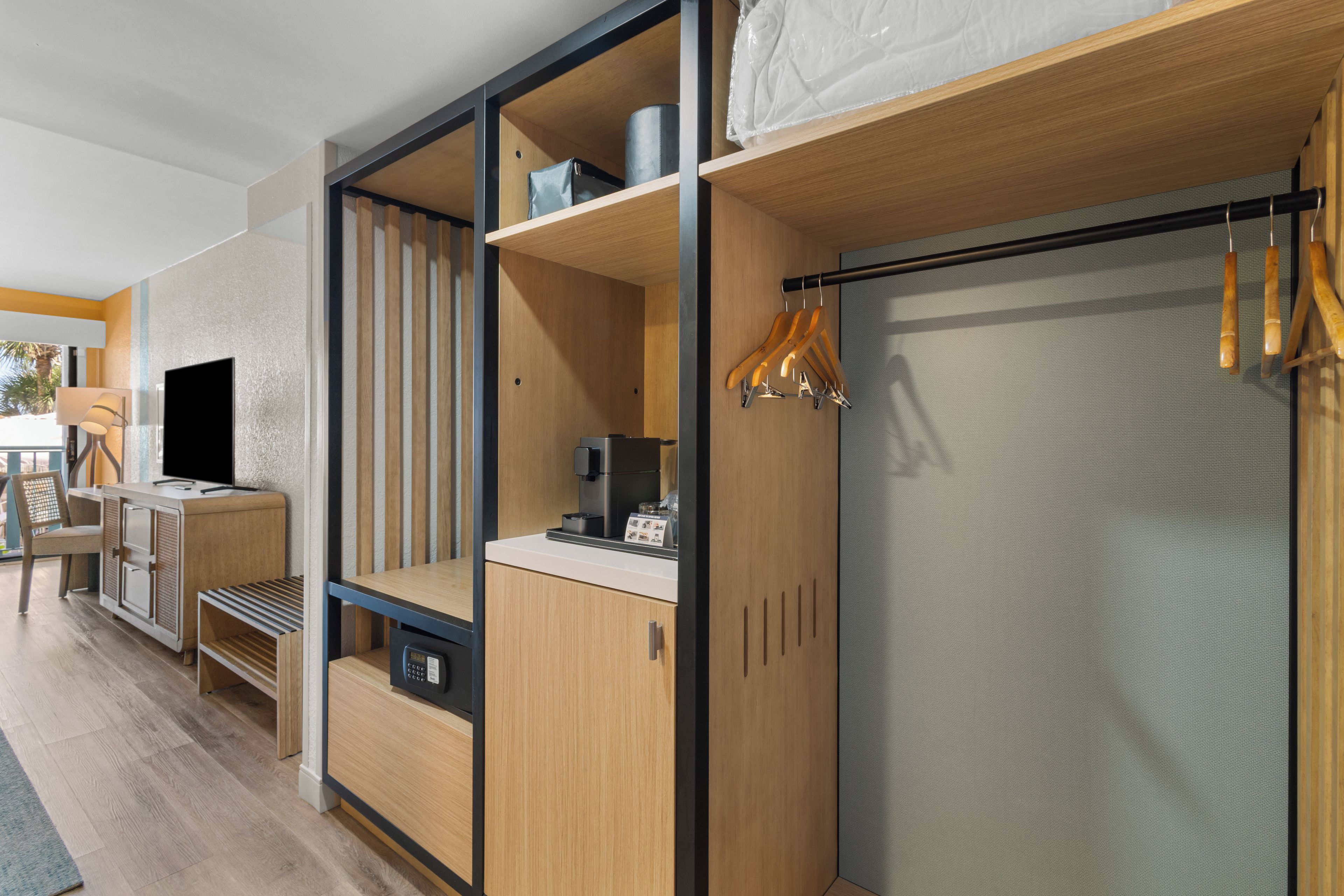 A modern hotel room with a bed, a desk, and a seating area.
