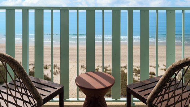 A balcony with a view of the beach and ocean.