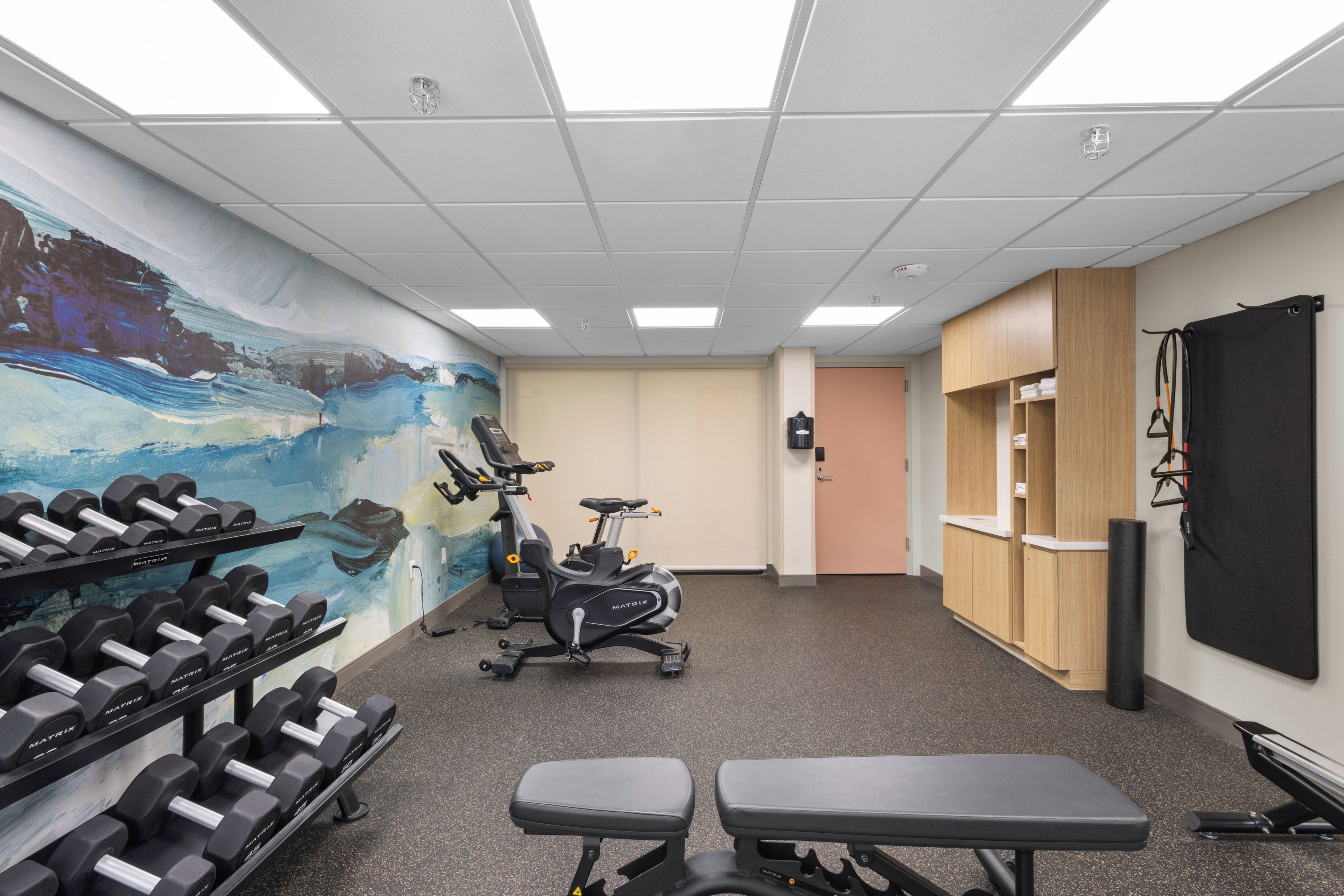 A gym with exercise equipment, a wall mural, and a reception area.