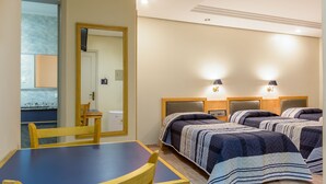 Habitación de hotel con tres camas, una mesa de comedor y sillas.