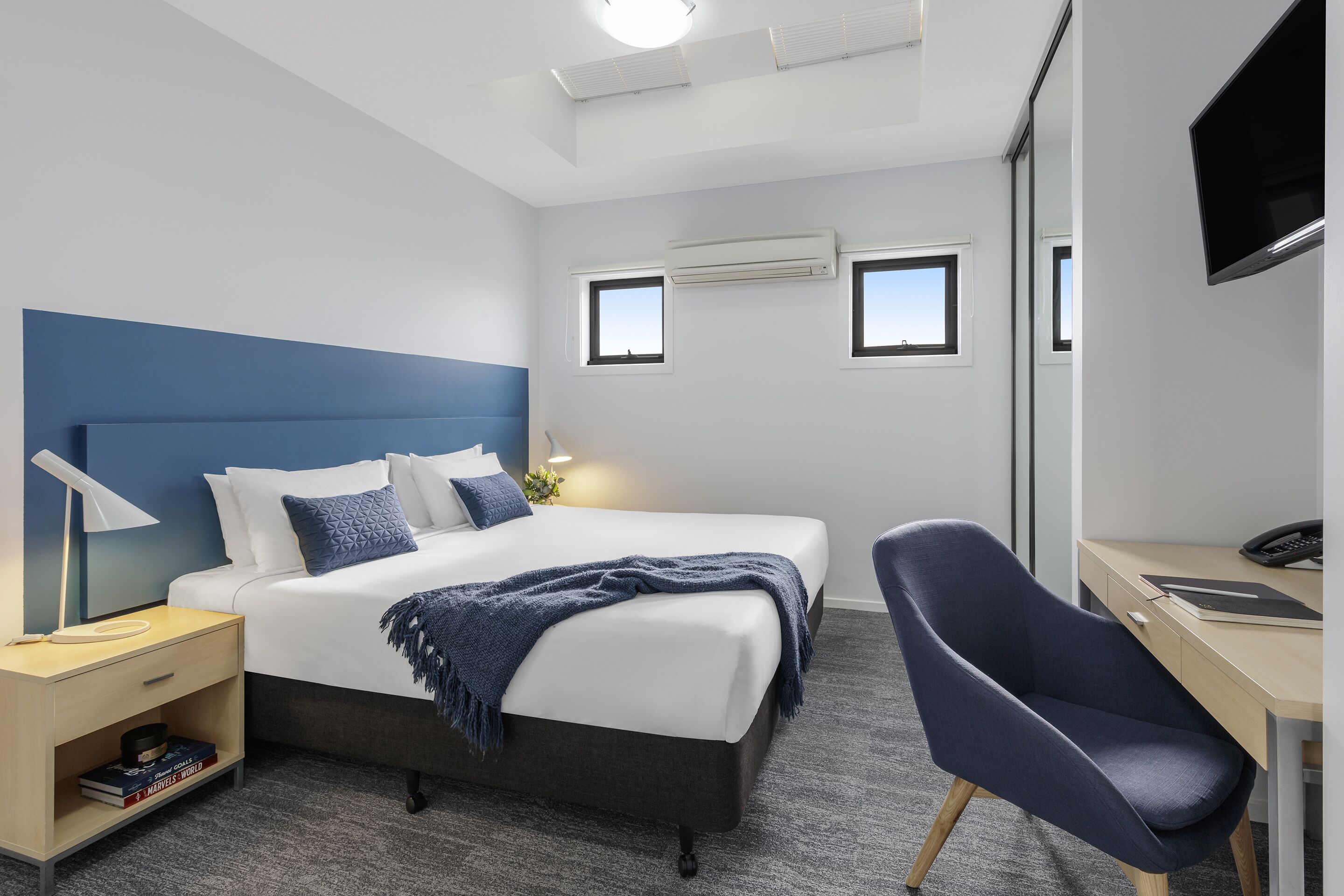 Une chambre d’hôtel moderne, dotée d’un grand lit, de tables de chevet, d’un bureau et d’une chaise.