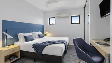 A modern hotel room with a large bed, bedside tables, a desk, and a chair.