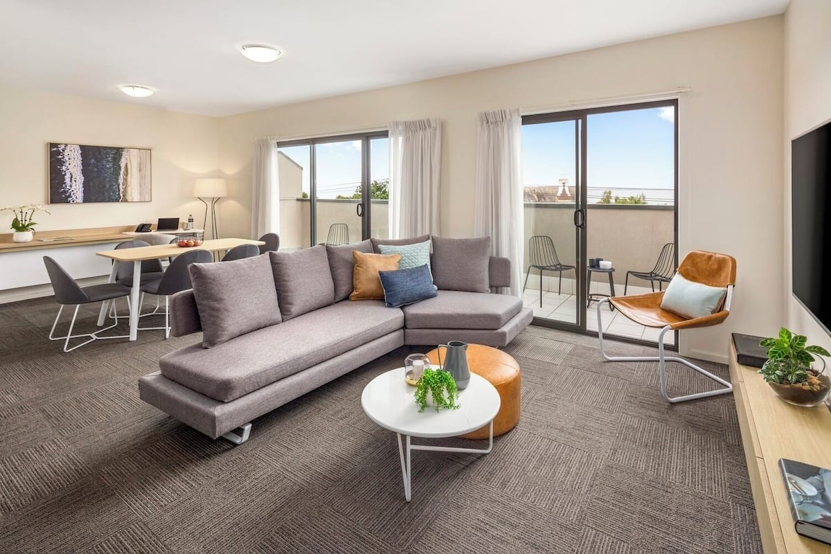 A modern living room with a grey sectional sofa, a round coffee table, and a dining area with a table and chairs.