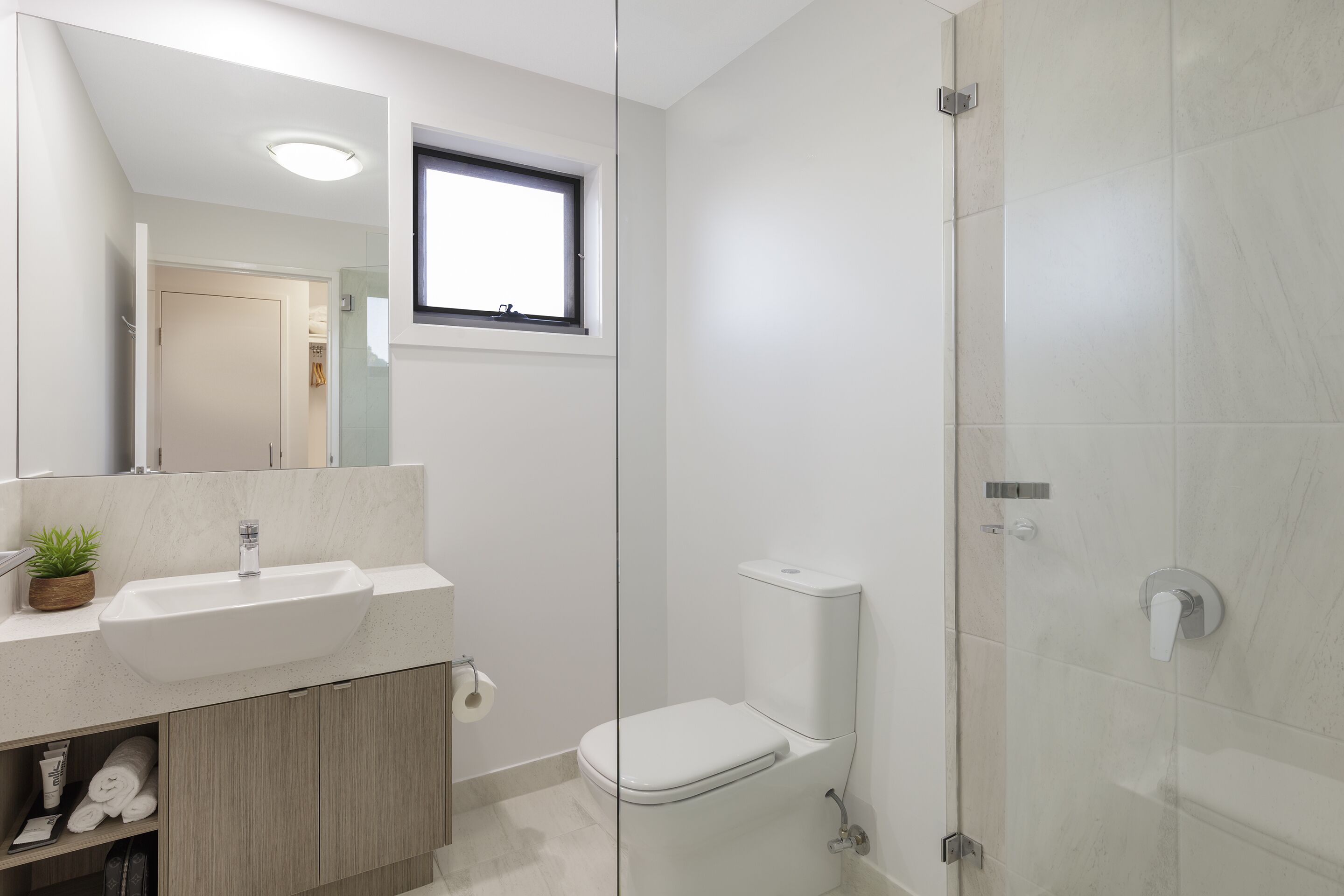 Une salle de bain moderne avec un grand miroir, un lavabo, des toilettes et un espace douche.