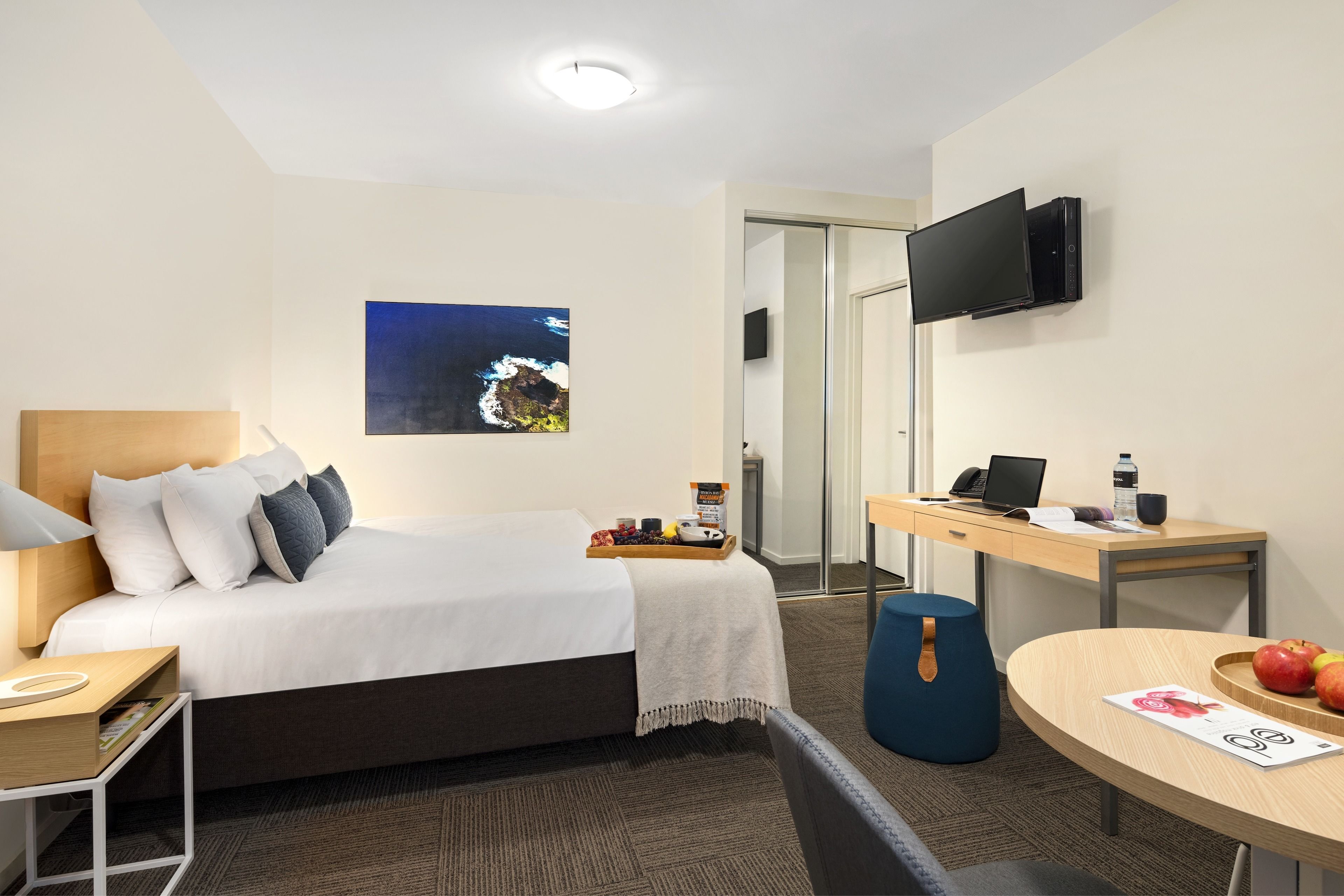Ein Hotelzimmer mit Bett, Schreibtisch, Fernseher und einem Bild an der Wand.
