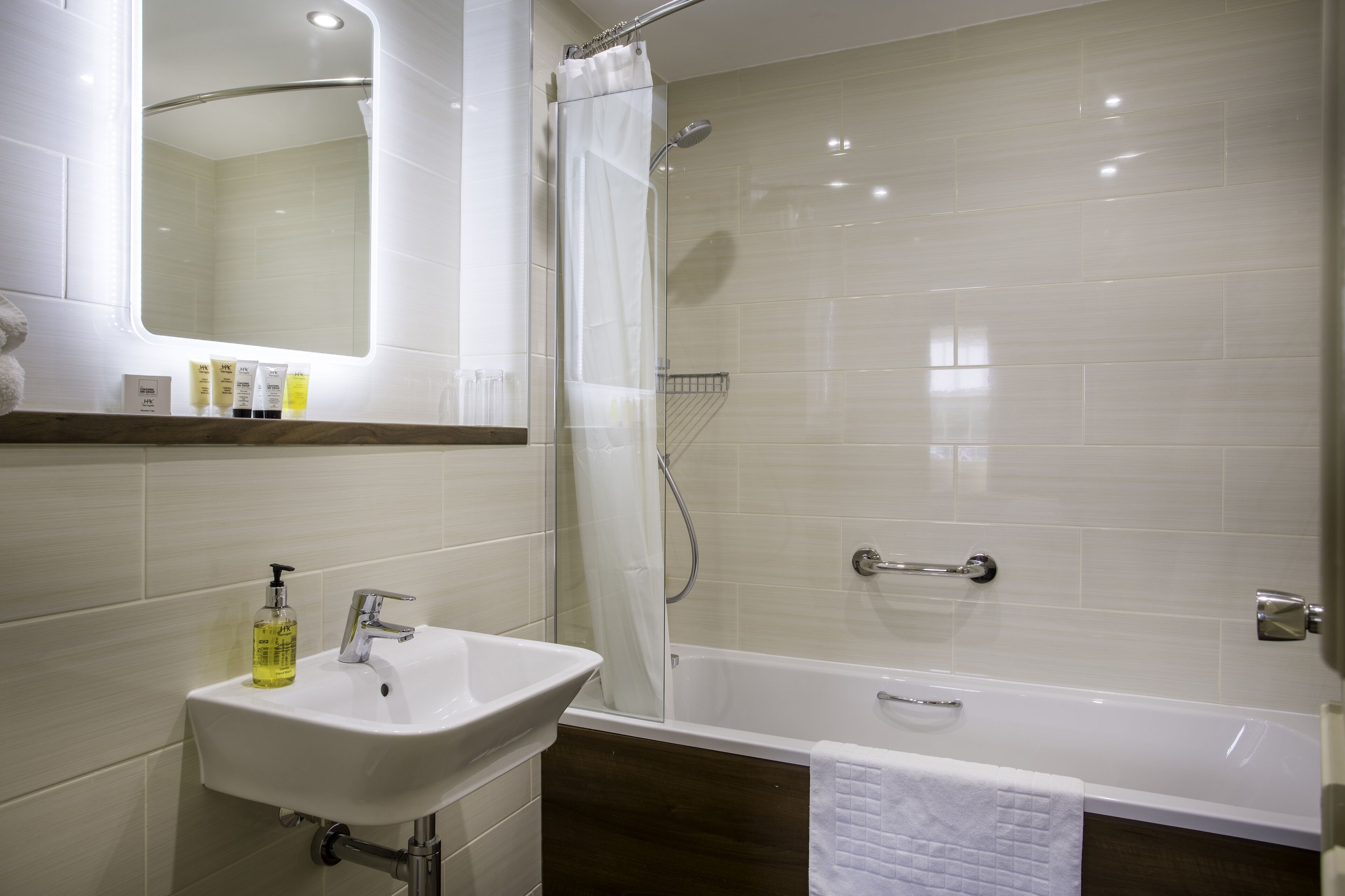 Een moderne badkamer met een witte wastafel, spiegel en badkuip.