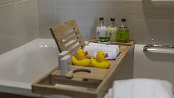 Una bandeja de madera con patitos de goma y artículos de aseo en un baño.