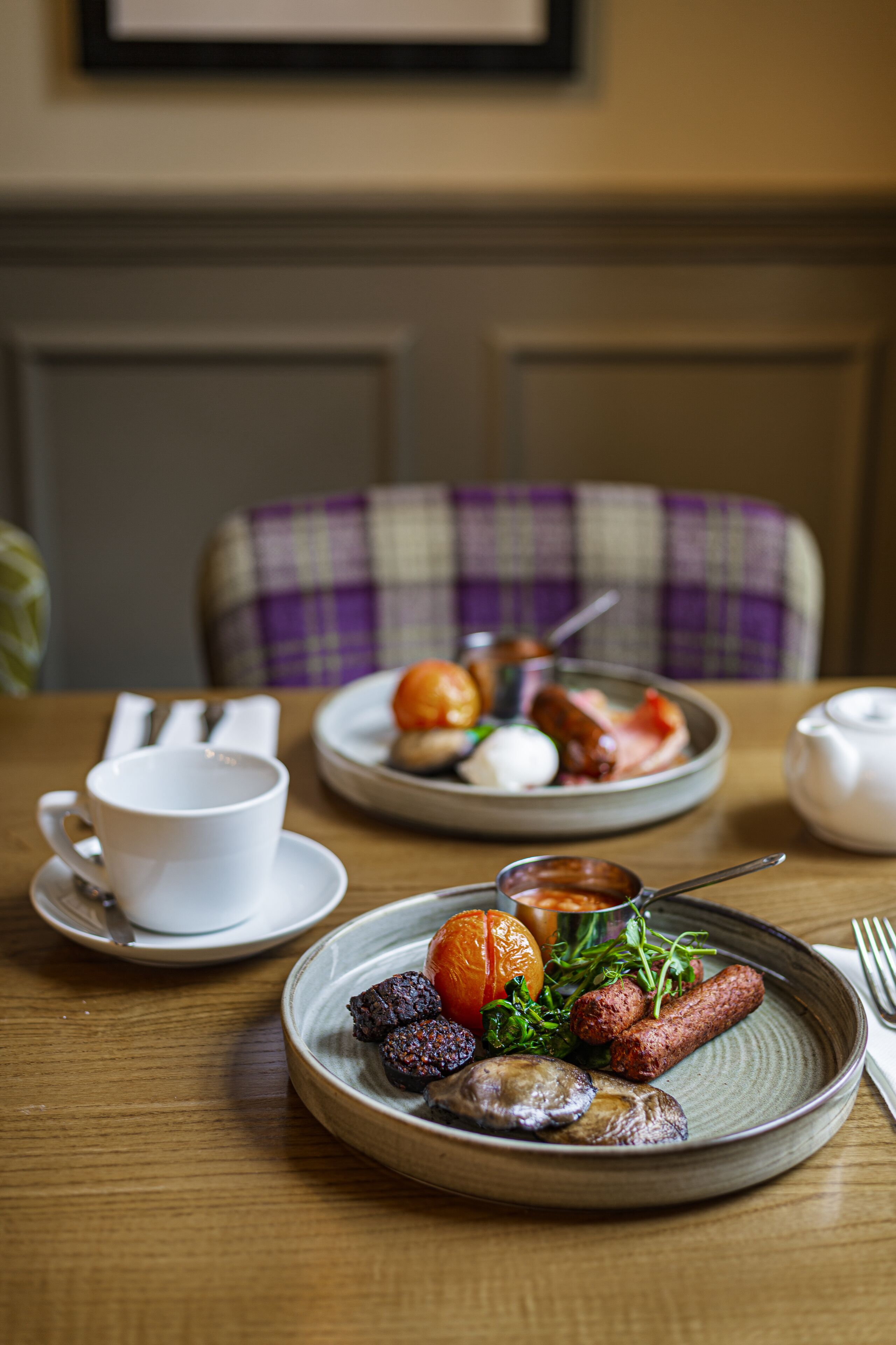 A dining table with plates of food, a cup, and a teapot.