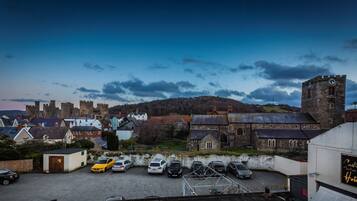 A castle hotel with a parking lot, stone buildings, and a tower.