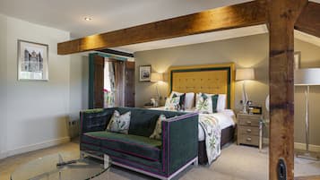 Un dormitorio con un sofá verde, una cama con cabecera de madera, una mesita de noche y una lámpara.
