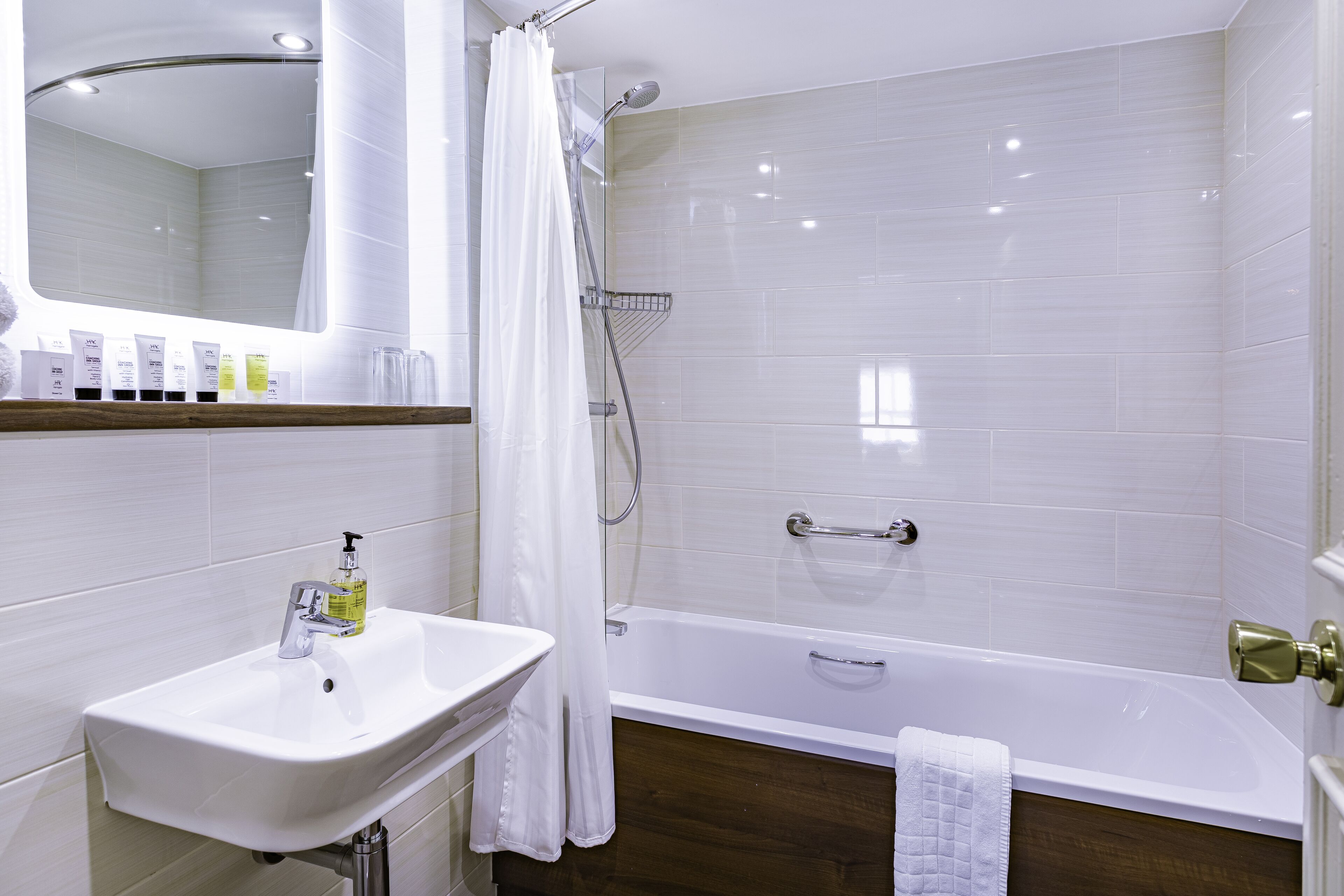 A bathroom with a white sink, mirror, and bathtub.