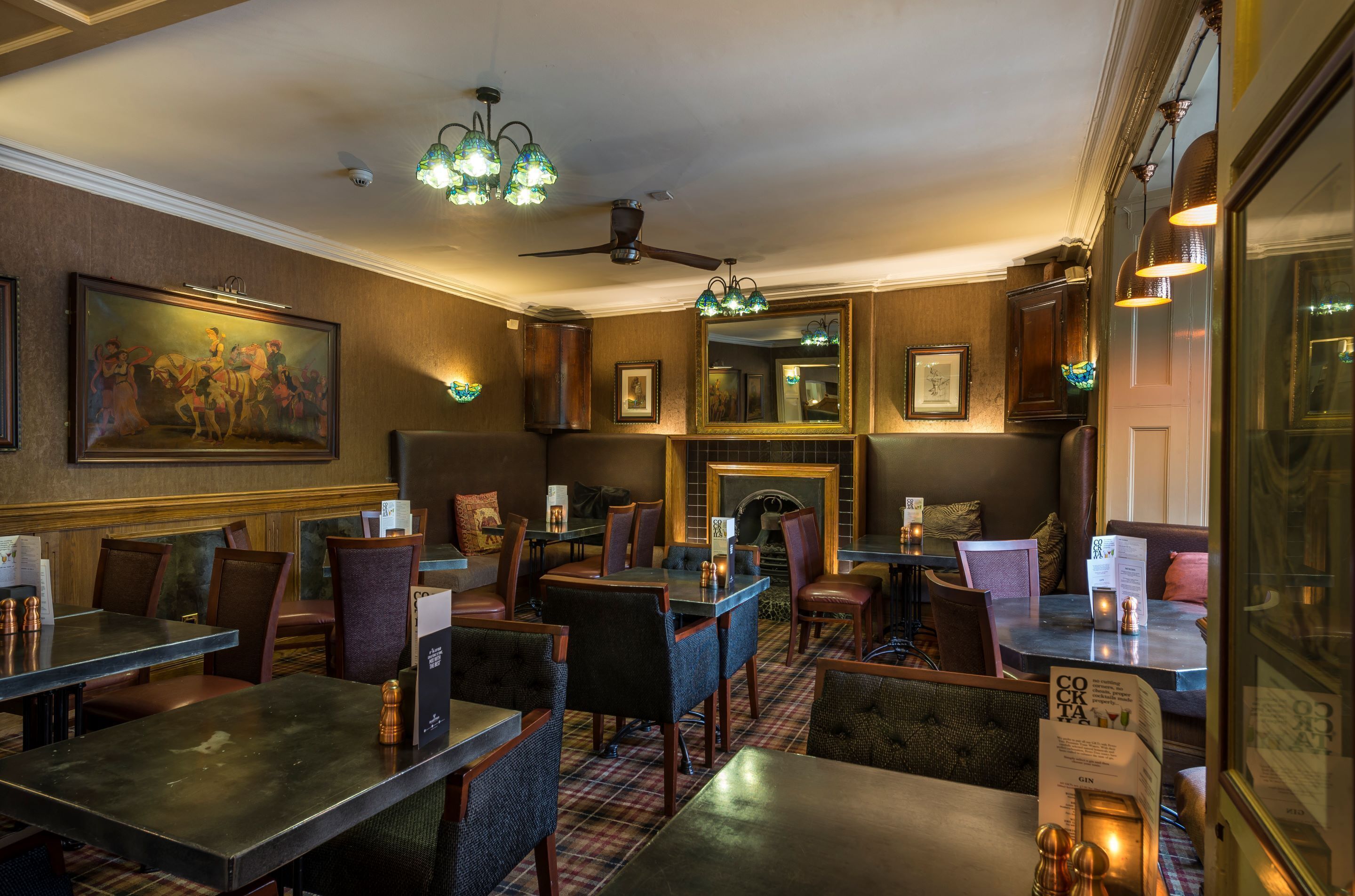 Un restaurante con mesas y sillas de madera, chimenea y ventilador de techo.