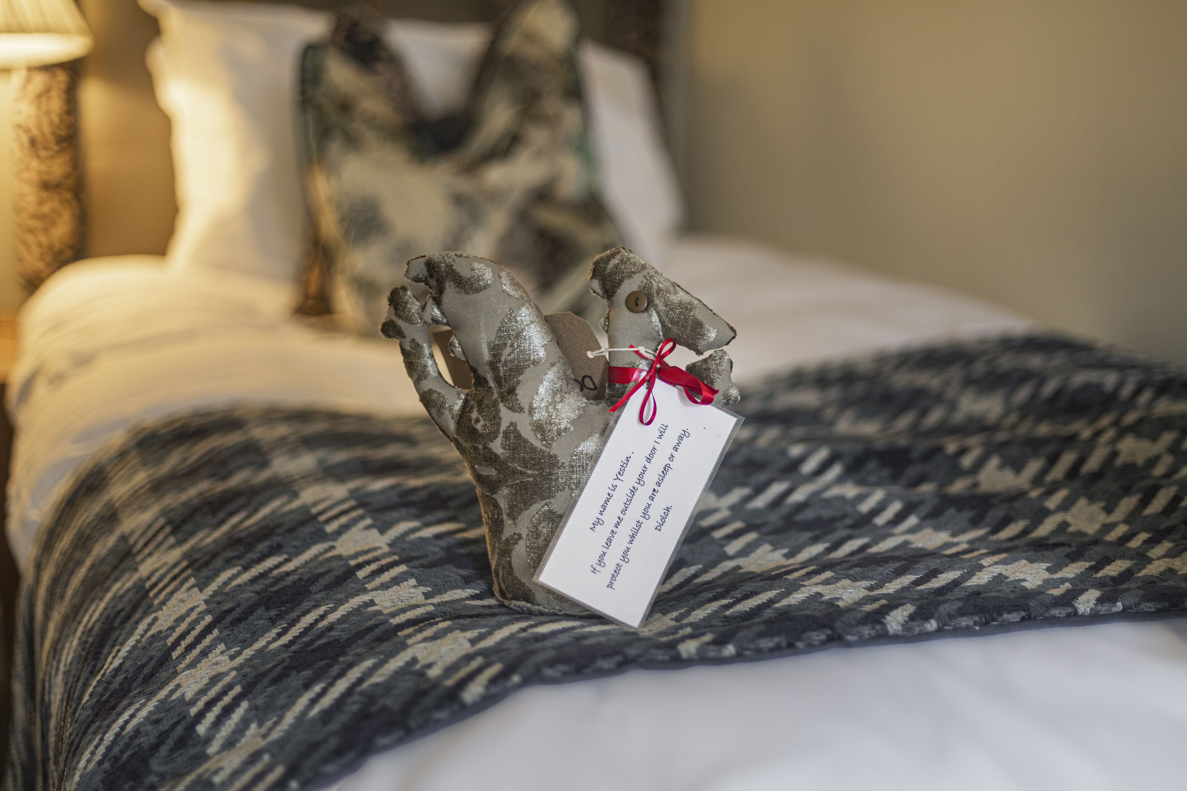 A bed with a patterned blanket and a decorative pillow.
